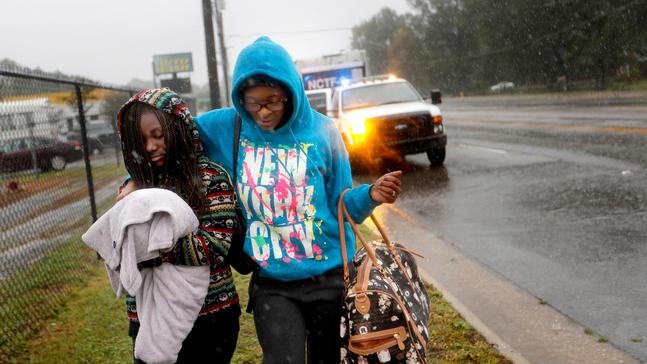 Candice Willis, right, and her daughter Naiya, 11, walk to a bus after being evacuated from their flooded neighborhood as Florence continues to dump heavy rain in Fayetteville, N.C., Sunday, Sept. 16, 2018. (AP Photo/David Goldman)