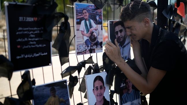 A youth from the Druze minority weeps over a makeshift memorial for 12 children and teens killed in a rocket strike on a soccer field, in the village of Majdal Shams, in the Israeli-annexed Golan Heights, Monday, July 29, 2024. (AP Photo/Leo Correa)